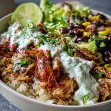 Zesty salsa and cool lime crema drizzled over a vibrant Carnitas Burrito Bowl.