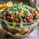 Easy Taco Dip Cups with layers of refried beans, sour cream, and cheese in clear cups, topped with lettuce, tomatoes, and green onions for a party-ready appetizer.