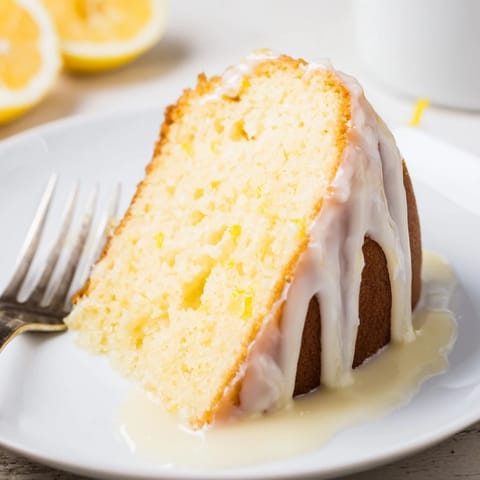 A sliced Lemon Pound Cake reveals a moist, buttery crumb, served with fresh berries on a rustic plate.