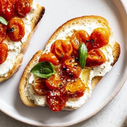 Savory Mediterranean-inspired toast featuring warm, caramelized tomatoes and smooth lemon-zested ricotta, served on rustic bread for a perfect breakfast or light snack.