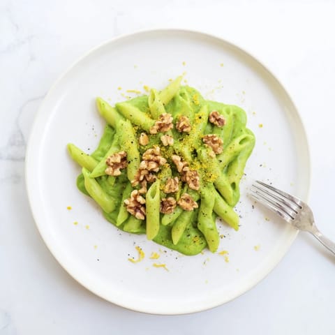 Creamy Spinach Walnut Pasta is served warm, tossed in a velvety green sauce with toasted walnuts and a sprinkle of lemon zest.