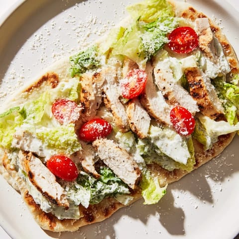 Freshly prepared Caesar Chicken Flatbread with juicy sliced chicken, crunchy lettuce, and a drizzle of tangy Caesar dressing.  