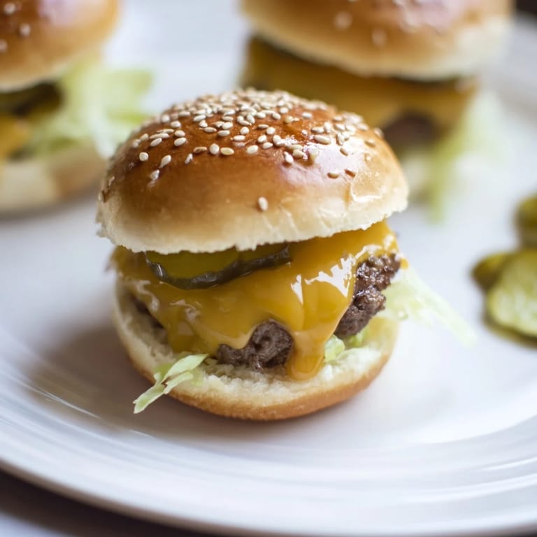 Stack of warm Sliders – Mini Hamburgers with special sauce dripping, served on a wooden board for a party crowd.