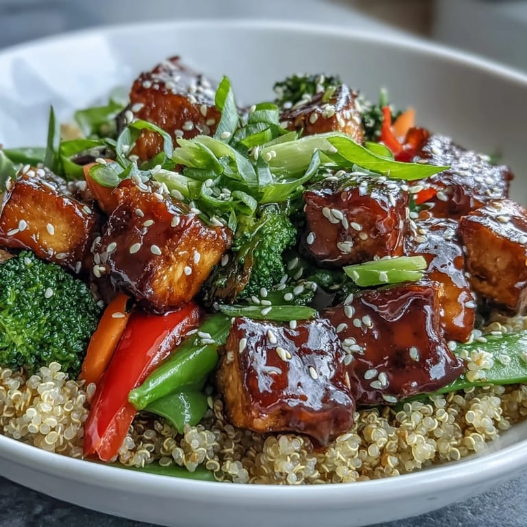 A close-up of the Quinoa Vegetable Teriyaki Bowl garnished with sesame seeds and fresh green onions, served steaming hot on a table.