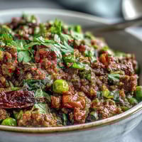 Freshly cooked Venison Keema Curry in a rustic bowl, garnished with cilantro and lemon wedges for a bright, zesty finish.