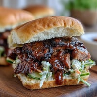 Smoky BBQ brisket piled high on soft slider buns with tangy sauce and crunchy slaw for a perfect party bite.