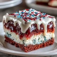 Festive red, white, and blue Patriotic Poke Cake topped with creamy white chocolate ganache.